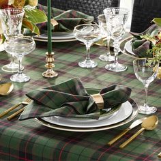 the table is set with green and red plaid napkins, gold place settings, silverware