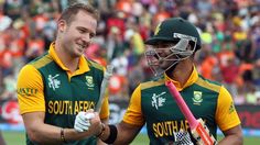 two men in green and yellow uniforms holding bats