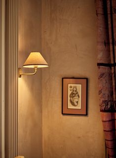 a lamp that is next to a wall with a picture hanging on it's side