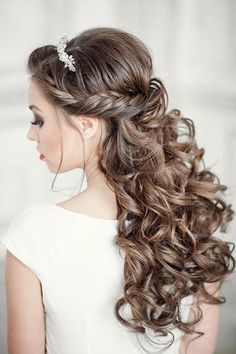 a woman with long curly hair wearing a white dress and a flower in her hair