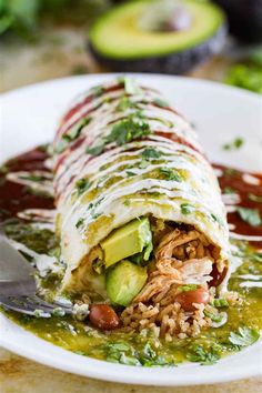 a white plate topped with an enchilada covered in meat and veggies