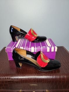 "These shiny black Jacqueline heeled loafers are GORGEOUS! I'm placing them from the 1960s to early 1970s era. They come in a black patent finish vinyl with red detail and gold buckles. They feature a 2\" block heel.  Condition: Great vintage condition with box. There are signs of wear but still a gorgeous pair of shoes! There is writing on the box (please see detailed photos).  Please view all pictures carefully as all vintage items are sold as is. Label: Jacqueline Label Size: 8.5 AA (narrow) Measurements: Heel Hight: 2\" ball width: 3\" Length: 10\" For more vintage and handmade women's and children's clothing please visit my shop: www.etsy.com/shop/WhimsyFair Thanks for visiting Whimsy Fair!" Retro Patent Leather Heels For Office, Retro Patent Leather Office Heels, Retro Almond Toe Patent Leather Heels, Retro Patent Leather Heels For Evening, Retro Patent Leather Evening Heels, Retro Heels With Red Sole And Almond Toe, Vintage Heels With Red Sole For Evening, Vintage Evening Heels With Red Sole, Sixties Party