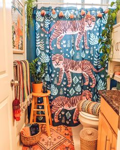 a bathroom with a tiger shower curtain and rugs on the floor in front of it