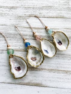 three different types of earrings on top of a white wooden table with blue beads and gold earwires