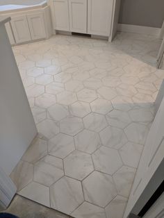 a bathroom with white cabinets and marble flooring