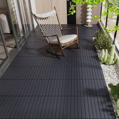 a rocking chair sitting on top of a black tile floor next to a green plant