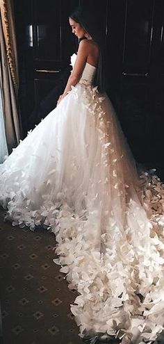 a woman in a wedding dress standing next to a large pile of paper machs