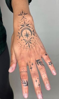 a woman's hand with tattoos on it and stars in the sky above her