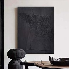 an abstract painting hangs on the wall next to a table with a bowl and vase