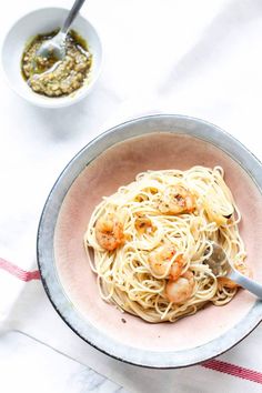 a bowl filled with pasta and shrimp on top of a table