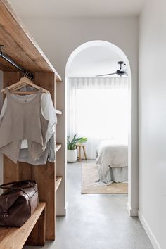 an open door leading to a bedroom with clothes hanging on the shelves and luggage in front of it