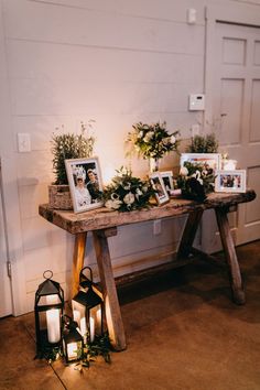 a wooden table topped with pictures and flowers next to a lantern filled candlelight holder