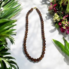 a brown beaded necklace sitting on top of a table next to flowers and plants