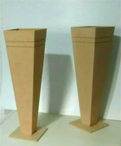 two brown vases sitting side by side on top of a white table next to each other