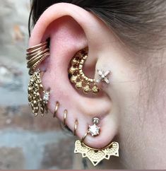 a woman wearing gold ear cuffs and piercings on her ears with an intricate design