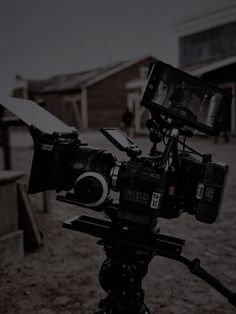 a video camera sitting on top of a tripod in front of a barn and building