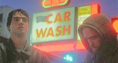 two people standing in front of a car wash sign