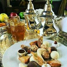 a white plate topped with lots of food next to two silver teapots on a table