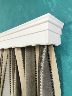 a close up of a curtain rod on a blue wall with green and white paint