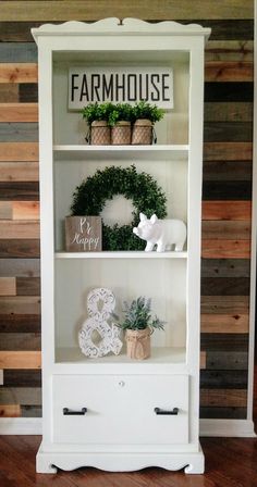 a white bookcase filled with plants and decorations