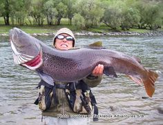 a man holding up a large fish in the water