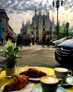 a table with coffee and pastries on it in front of a castle like building