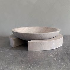 a large white bowl sitting on top of a cement slab next to a smaller one