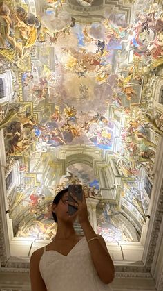 a woman taking a selfie in front of a ceiling with many paintings on it