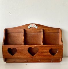 a wooden shelf with three heart shaped compartments