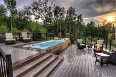 a deck with chairs and an above ground swimming pool in the middle of it, surrounded by trees