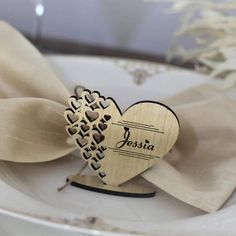 a white plate topped with a wooden heart shaped decoration next to a beige bow tie