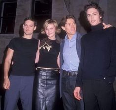 three men and a woman standing next to each other