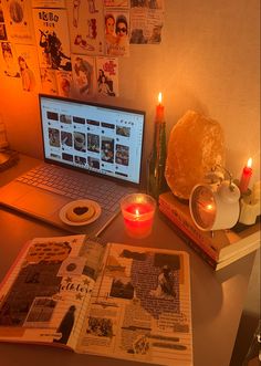 a laptop computer sitting on top of a desk next to a book and candle holder