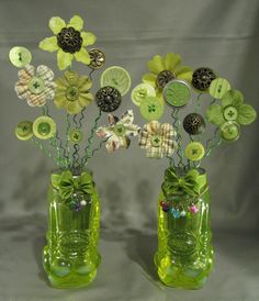 two green vases with buttons and flowers in them