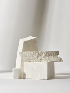 three blocks of cement stacked on top of each other in front of a white wall