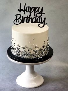 a white and black birthday cake sitting on top of a table