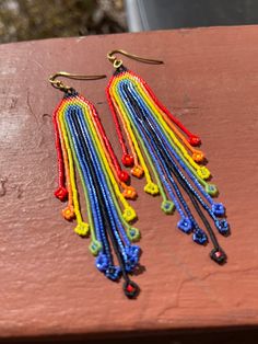 two pairs of multicolored beaded earrings sitting on top of a wooden table