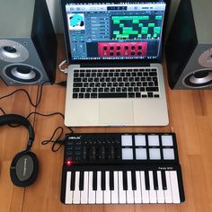 a laptop computer sitting on top of a wooden desk next to a keyboard and headphones