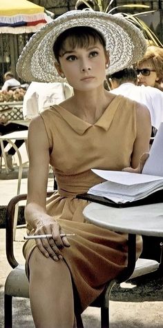 a woman sitting at a table wearing a hat