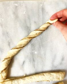 a person holding a piece of bread in their left hand on a marble counter top