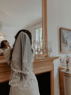 a woman standing in front of a mirror wearing a veil