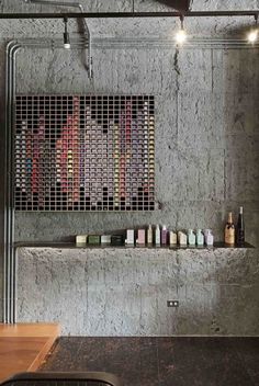 a shelf with some bottles on it in a concrete room next to a counter top