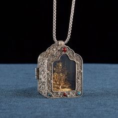 an ornate silver locke with a painting on it's front and back sides hanging from a chain