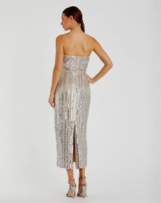 a woman is wearing a silver dress with sequins on the skirt and heels