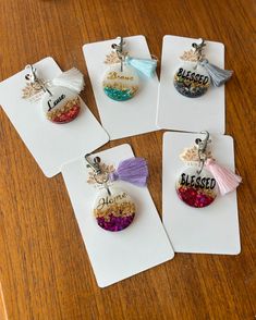 four tags with words and tassels on them sitting on a wooden table top