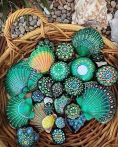 sea shells are sitting in a wicker basket on the ground next to some rocks