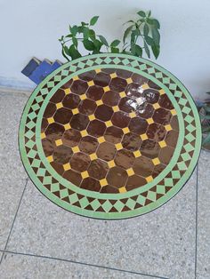 a green and brown table sitting on top of a floor next to a potted plant