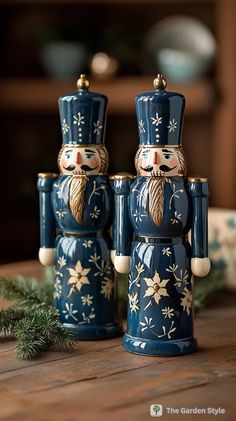 two blue nutcrackers sitting on top of a wooden table next to a pine branch