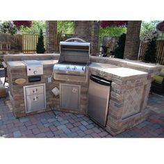 an outdoor kitchen with grill, sink and oven in the middle of brick pavers