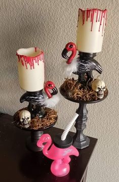 two halloween candles with fake skulls and flamingos on them, sitting on a table